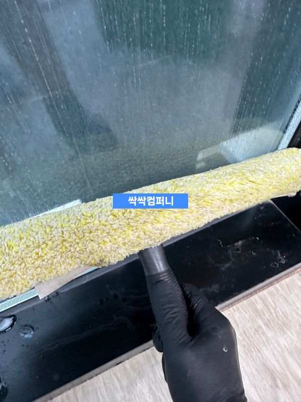 사무실 창문 틀 청소 작업 중인 모습으로, 파란색 천을 사용하여 창틀의 먼지와 오염물을 제거하고 있습니다.