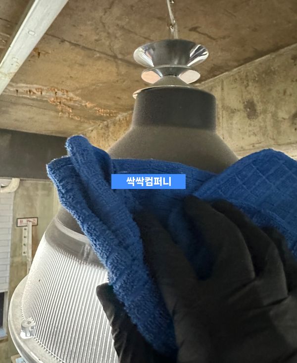 천장 조명 기구를 청소하는 과정으로, 파란색 청소용 천으로 둥근 조명 마운트를 닦고 있는 모습입니다.