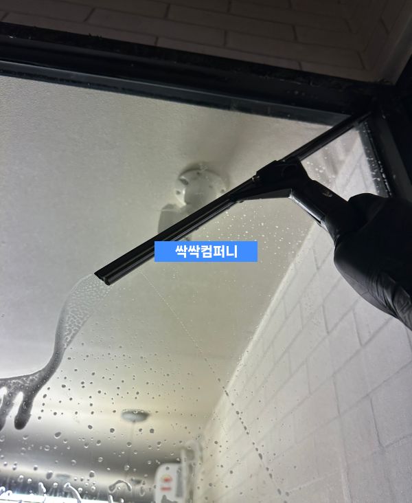 a hand holding a squeegee cleaning a window