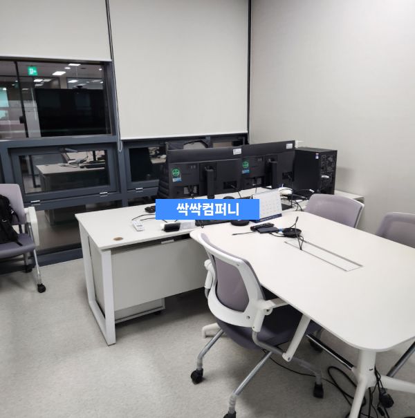 깔끔하게 정돈된 사무실 공간으로, 흰색 책상과 의자가 배치되어 있고 벽면에는 수납장이 설치되어 있습니다.